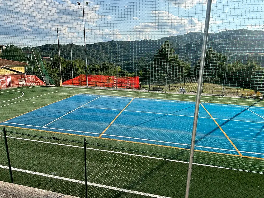 Campo da tennis azzurro all'aperto con recinzione