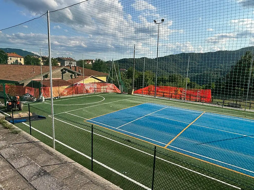 Campo da tennis azzurro in erba sintetica con rete